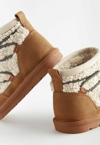 Stivali alla caviglia in suede marrone con parte superiore in finta shearling crema, caratterizzati da accenti grigi e un colletto imbottito. Suola in gomma testurizzata.