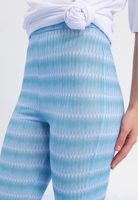 Blå och ljusrosa mönstrade leggings med vertikal ribbning, som har en hög midja och en åtsittande design, accentuerade på sidan.