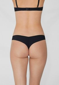 Schwarze String-Unterwäsche aus einem glatten, elastischen Stoff, minimalistischem Design und nahtlosem Abschluss. Die Rückansicht hebt den niedrigen Schnitt hervor.