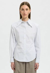 Camicia a righe bianca e azzurro chiaro, con colletto ampio, maniche lunghe e orlo arrotondato. Il tessuto sembra liscio e fresco.