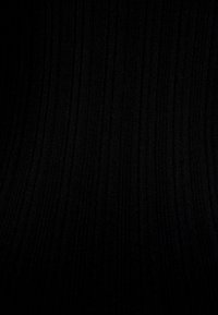 Texture di tessuto ribbed nero con linee verticali che creano un sottile motivo a strisce e un aspetto morbido e lavorato a maglia.
