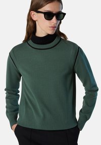 Maglione verde a maglia con colletto alto nero, polsini e orlo a coste. Presenta dettagli bicolore lungo le spalle per un contrasto aggiuntivo.