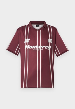 Burgundijas sporta krekls ar baltām vertikālām svītrām, V veida kakla izgriezums un logo "Monterrey Core Sport 1990" centrā uz krūtīm.