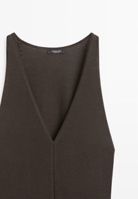 Dunkelbraunes ärmelloses Stricktop mit tiefem V-Ausschnitt und sichtbarer zentraler Naht, leichter Stoff, Etikett am hinteren Halsausschnitt.
