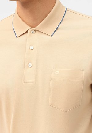 Polo beige con tejido texturizado, con cuello clásico, tres botones y un detalle azul en el cuello. Incluye un pequeño bolsillo en el pecho.