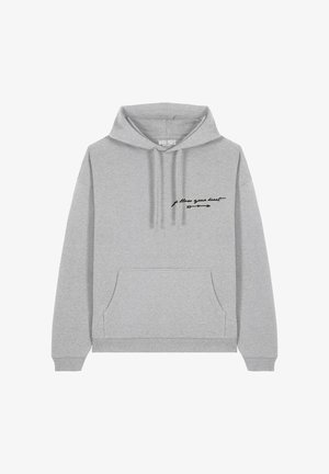 Grijze hoodie van zachte stof, met een voorzak en een capuchon met trekkoord. "Volg je hart" tekst in zwart op de borst.