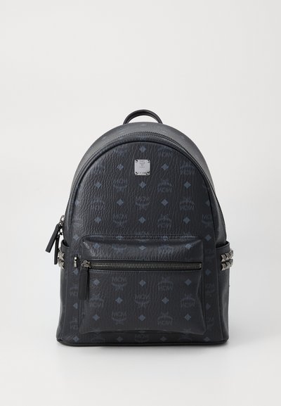Black leather backpack with embossed logo pattern, rounded shape, top handle, front zip pocket, and silver-tone studs on the side accents.