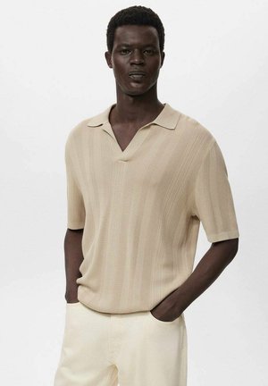 Beige pletená polo košile s krátkým rukávem a véčkovým výstřihem, s jemnými texturovanými pruhy, spárována se světlými kalhotami.