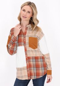Rutigt skjorta i orange, beige och vitt med patchworkdesign. Har en manchesterficka och texturerade ärmar.