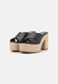 Sandalias de plataforma de cuero negro con diseño de tiras cruzadas, suela de yute trenzado y tacón grueso. Punta abierta con plantillas texturizadas.