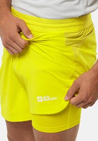 Felgekleurde gele sportshorts met een rekbare tailleband, voorzien van een logo op het been en een geprofileerde zijpaneel voor extra detail.