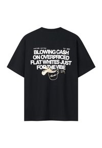 Camiseta negra con texto blanco "GASTANDO DINERO EN FLAT WHITES CAROS SOLO POR EL AMBIENTE" y una pequeña ilustración de una taza de café.