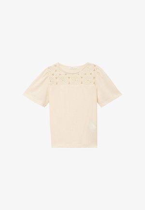 Blouse crème à manches courtes avec encolure ronde et détails en dentelle crochetée sur la partie supérieure de la poitrine et les épaules.