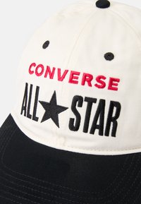 Vit och svart basebollkeps med broderad "CONVERSE" i röd och "ALL★STAR" i svart, med sydda detaljer och ventilationshål.
