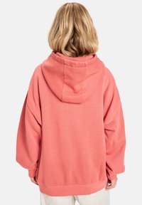 Oversized coral hoodie with a drawstring hood, ribbed cuffs, and hem. Made from soft fabric with a smooth texture.