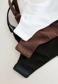 Stak af bomuldsansigtsmasker i hvid, brun og sort, der viser syede kanter og øreloops på en lys overflade.