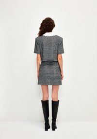 Zwart-wit geblokte twee-delige outfit met een cropped top met korte mouwen en een strakke mini-jurk, gecombineerd met zwart knielang laarzen.