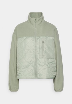 Světlý zelený fleecový kabát s prošívaným předním panelem, vysokým límcem, celým zipem, elastickými manžetami a zipovou kapsou na hrudi.