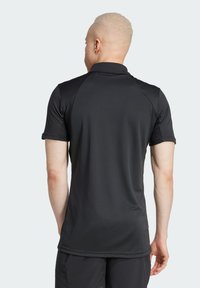Sort kortærmet polo med en glat tekstur og en lige pasform. Har en krave og et mærke ved den nederste søm. Ingen mønstre eller accenter.