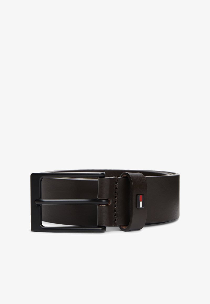 Ceinture en cuir marron foncé roulée avec une boucle rectangulaire noire et un petit logo rectangulaire de drapeau rouge, blanc et bleu sur la boucle de ceinture.