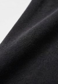Gros plan d'un tissu noir lisse et finement tissé avec des plis diagonaux subtils et de fins détails de texture.