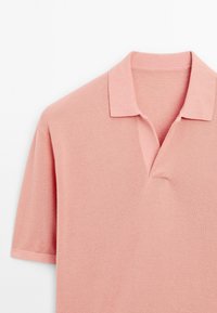 Kortärmad polo i mjuk rosa, med en strukturerad stickad tyg, klassisk krage och en partiell knappslå med en subtil V-formad halsringning.