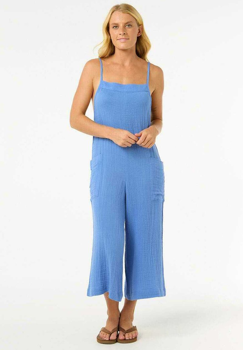 Mono de algodón azul con un ajuste relajado, tirantes spaghetti y bolsillos frontales. Presenta una tela texturizada y un diseño de pernera ancha y corta.