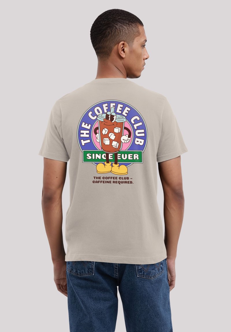 Beige cotton t-shirt featuring a colorful graphic on the back, depicting a cartoon character and text related to "The Coffee Club."