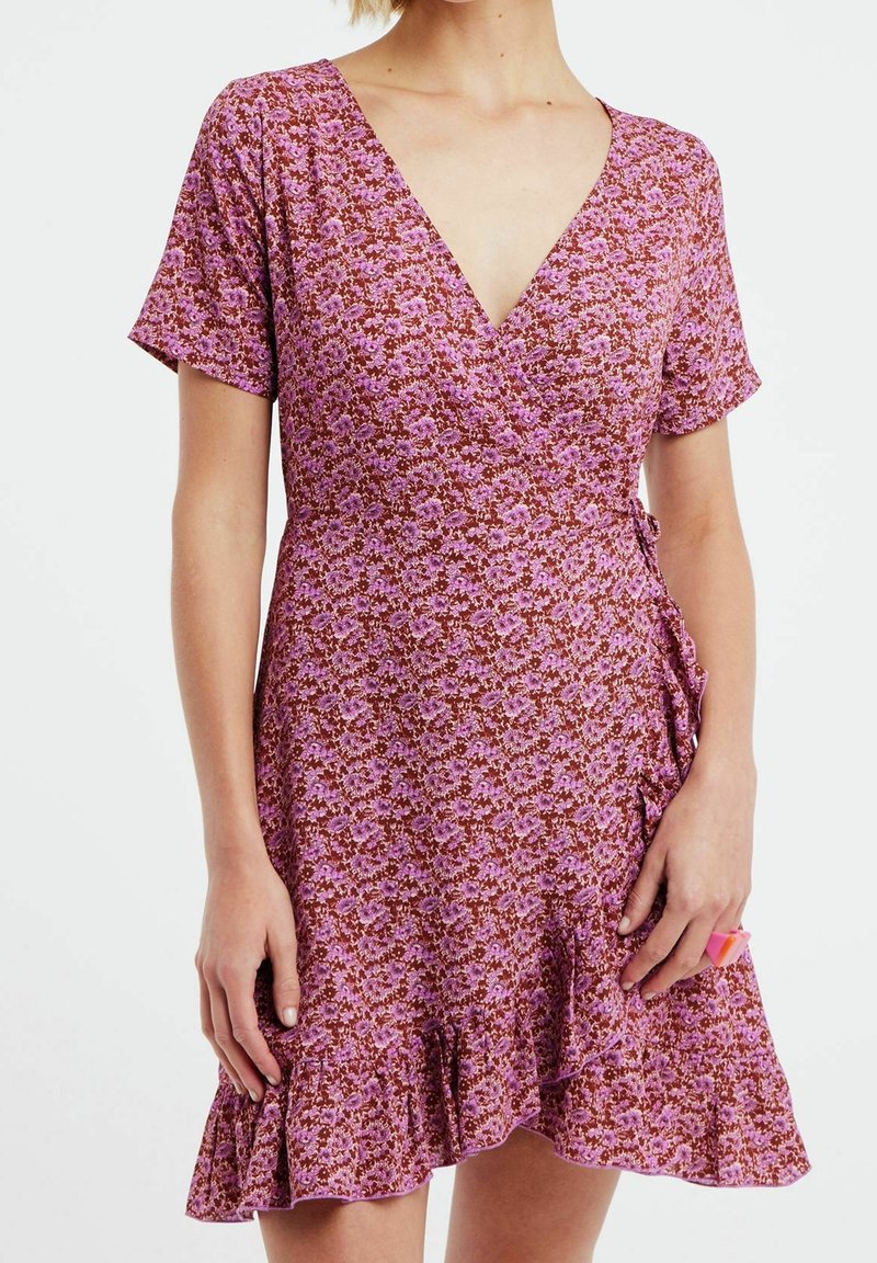 Vestido envolvente de manga corta en un estampado floral rosa y marrón con escote en V y dobladillo con volantes. Tejido ligero y suave.