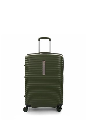 Valigia rigida verde scuro con manico telescopico e quattro ruote rotanti, in posizione verticale su uno sfondo bianco.