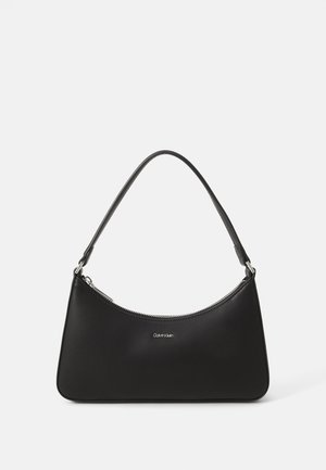 Sac à épaule en cuir noir avec fermeture éclair incurvée en haut et une seule bandoulière, avec petit logo Calvin Klein centré à l'avant.