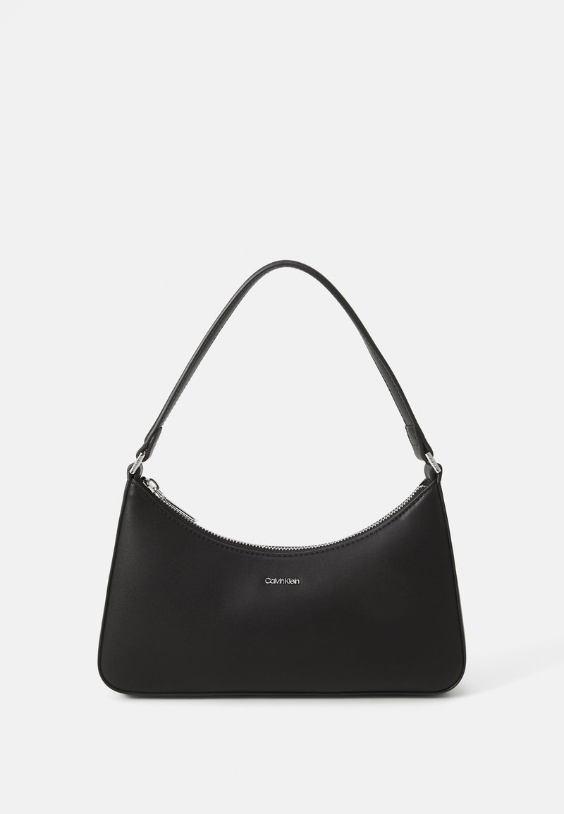 Sac à épaule en cuir noir avec fermeture éclair incurvée en haut et une seule bandoulière, avec petit logo Calvin Klein centré à l'avant.