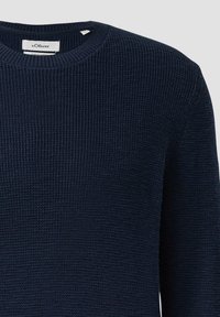 Granatowy sweter wykonany z organicznej bawełny, z teksturowanym, prążkowanym wzorem i okrągłym dekoltem. Metka przymocowana wewnątrz dekoltu.