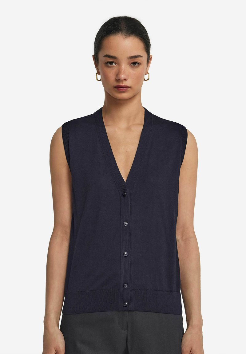 Mörkblå ärmlös cardigan med V-ringning, knäppning fram och ribbad kant. Tillverkad av ett mjukt tyg, med subtila stygnsdetaljer.