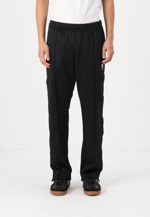 Czarne spodnie dresowe z elastycznym pasem, bocznymi kieszeniami na zamek oraz detalem z logo na lewej udzie, wykonane z lekkiego, gładkiego materiału.