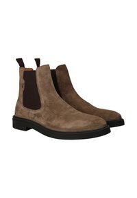 Bruine suède Chelsea-boots met elastische zijpanelen, platte zwarte rubberen zool en trekbanden voor eenvoudig aan- en uittrekken. Vlotte textuur, ronde neus.