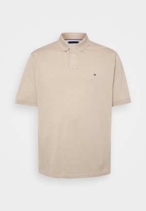 Beige Poloshirt aus Baumwolle; mit Kragen, kurzen Ärmeln und kleinem Logo auf der Brust. Glatte Textur, klassischer Schnitt.