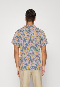 Kurzärmeliges Hemd mit einem mehrfarbigen abstrakten Blumenmuster auf blauem Hintergrund. Hergestellt aus leichtem Stoff mit entspannter Passform.