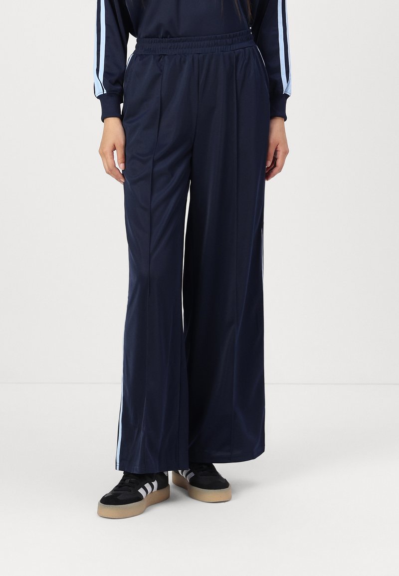 Calças largas azul marinho feitas de tecido suave, com cintura elástica e riscas laterais azul claro para um detalhe adicional.