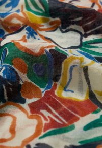 Tessuto multicolore con motivi floreali e geometrici astratti. Texture leggera e trasparente con blu, verdi, rossi e gialli vivaci.