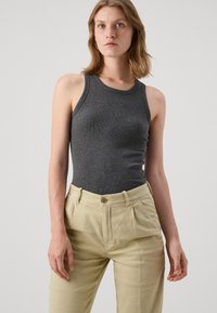 Top de tirantes gris con canalé y escote redondo, combinado con pantalones plisados beige claro que cuentan con cierre de botón y bolsillos laterales.