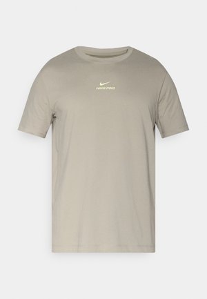 Maglietta grigia a maniche corte in morbido cotone con scollo rotondo; presenta un logo riflettente "Nike Pro" in giallo chiaro.