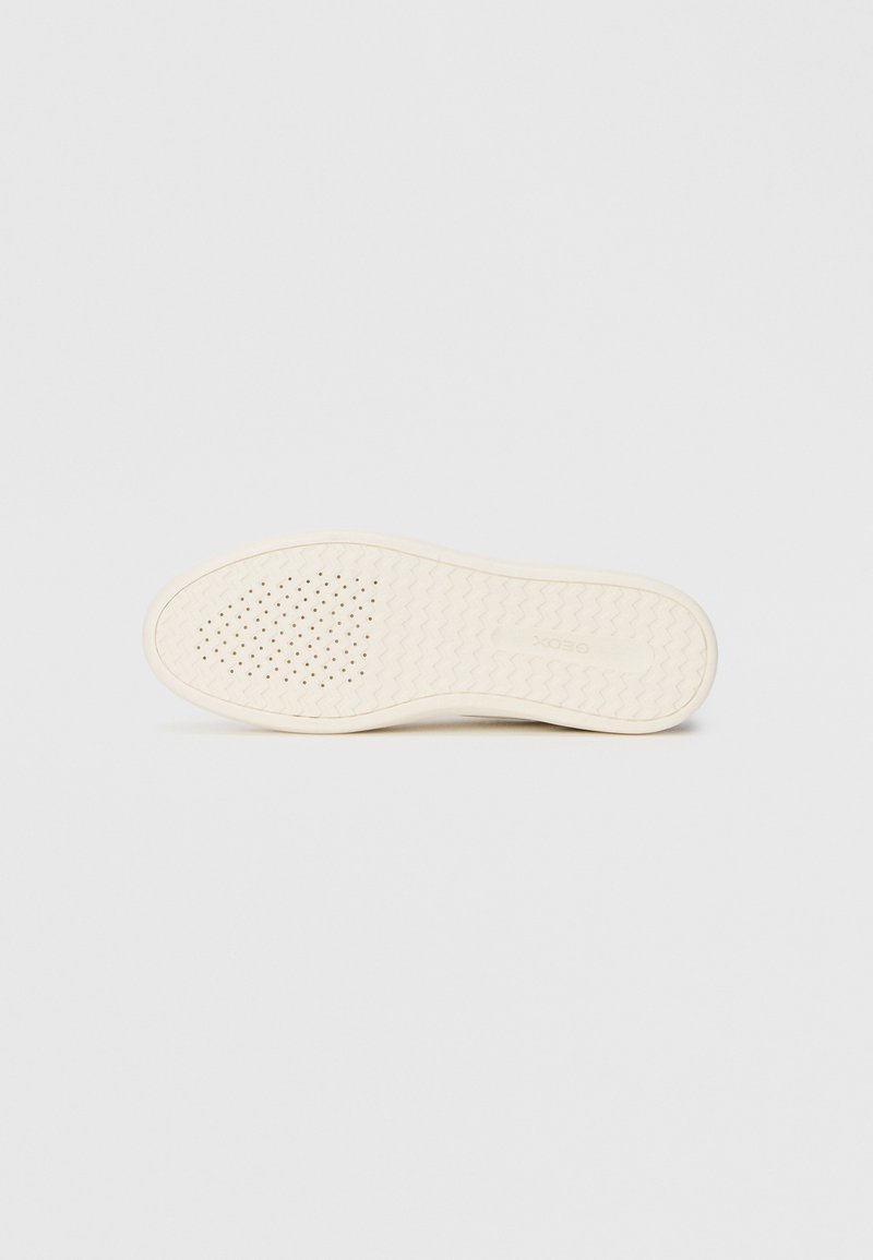 Semelle de chaussure en caoutchouc blanc cassé avec une surface texturée, comportant de petites perforations pour la ventilation et un motif de semelle en zigzag pour l'adhérence.
