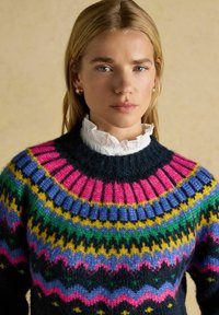 Mnohofarebný pletený sveter s okrúhlym výstrihom, prevažne tmavomodrý, s ružovými, zelenými, žltými a modrými vzorovanými akcentmi.