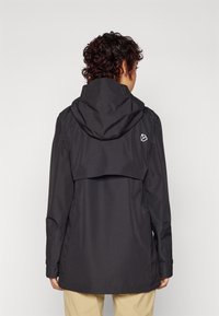 Giacca impermeabile nera con cappuccio, aletta di ventilazione posteriore e dettagli minimi del logo. Presenta polsini elastici e una silhouette dritta.