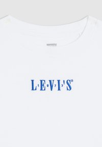 Balta medvilnės marškinėliai su mėlynai siuvinėtu "LEVI'S" logotipu. Apvalus kaklas ir lygus tekstūra, su minimalistišku dizainu.