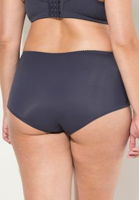 Slips a vita alta blu navy realizzato in tessuto morbido, con un design senza cuciture e cuciture sottili lungo i bordi per un comfort superiore.