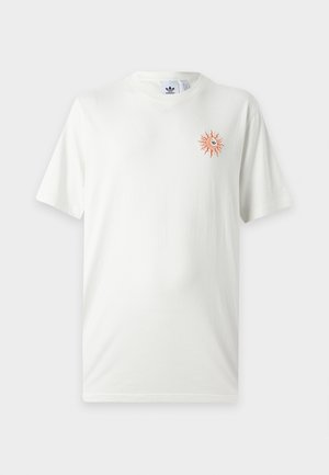 T-shirt blanc Adidas avec un petit motif de soleil orange sur le côté gauche de la poitrine et un col rond.