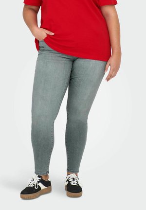 Gray skinny jeans with a smooth texture, paired with a red shirt and black sneakers featuring white and tan accents. Casual outfit focus.