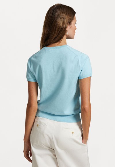 Top in maglina azzurro chiaro a maniche corte con scollatura rotonda, caratterizzato da un design aderente e una texture liscia. Lunghezza cropped e orlo a costine.